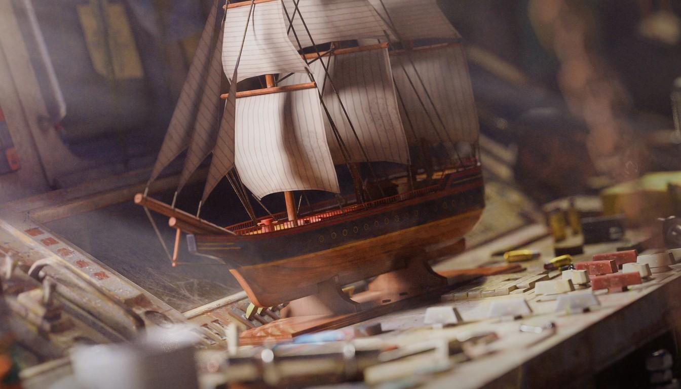 A sailing ship model on a cluttered workbench with small parts and tools