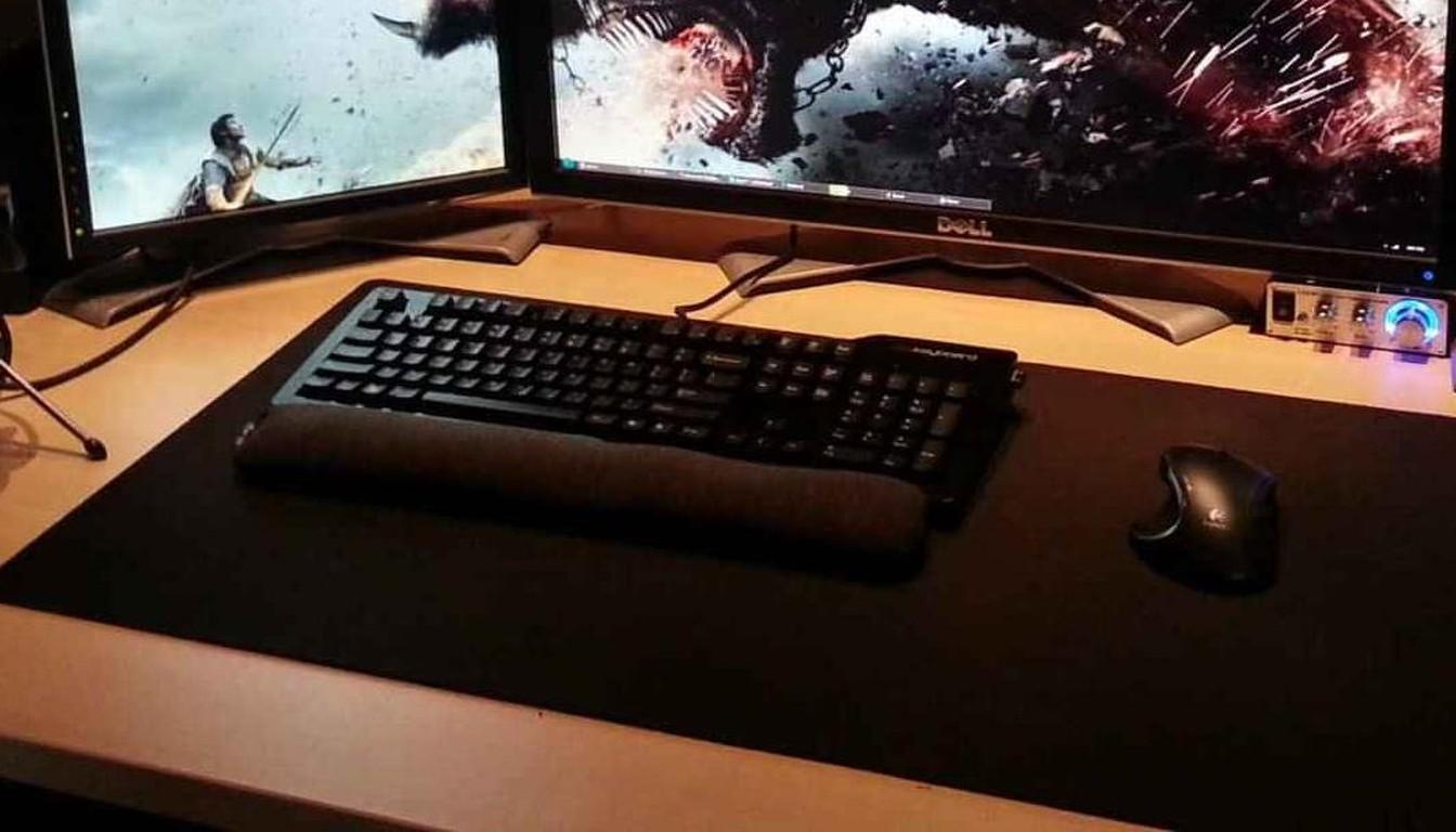 Gaming mouse and keyboard on a large mousepad in front of monitors