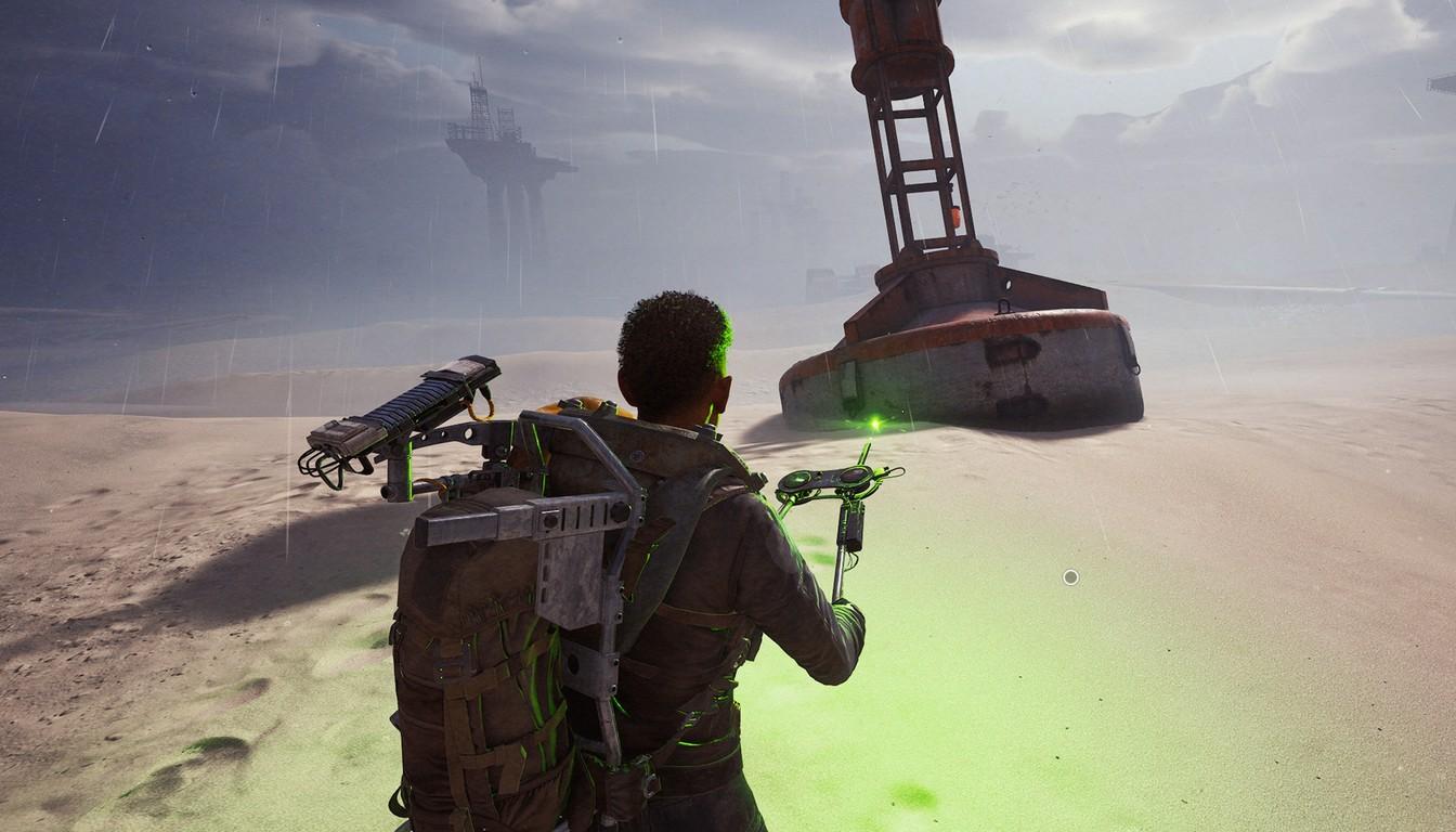 A Raider holding a gadget on a sandy shore with a rusty tower behind