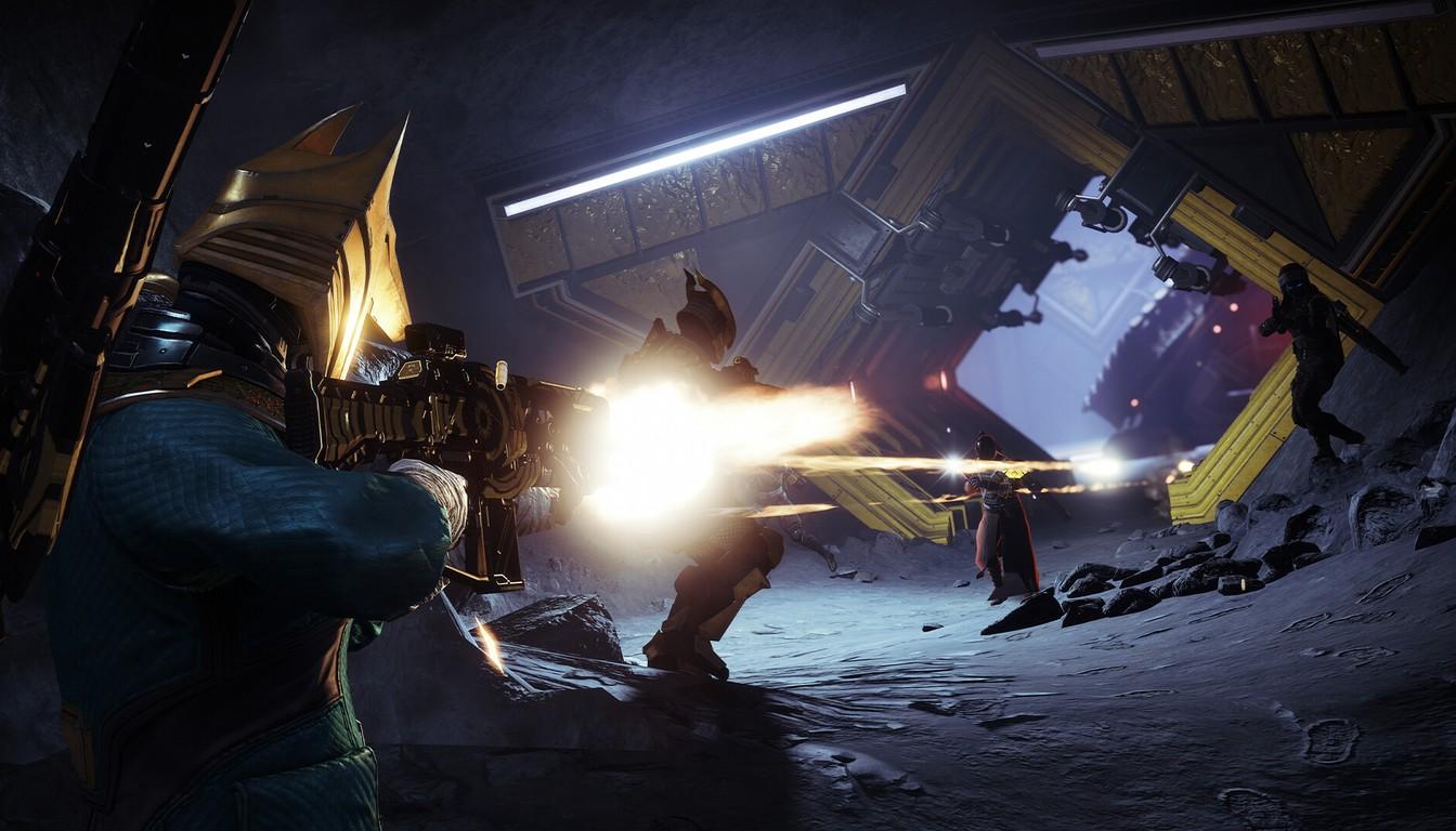 A Guardian firing a rifle in a dark ruined chamber with teammates nearby